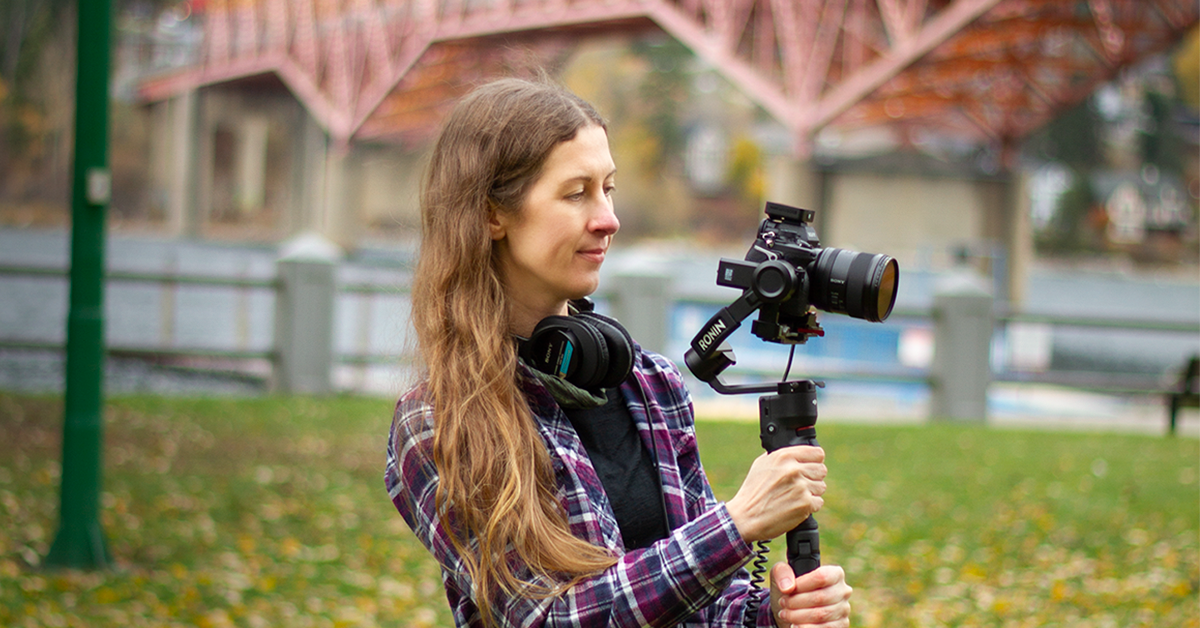 Jessica holding a camera and gimbal outdoors.